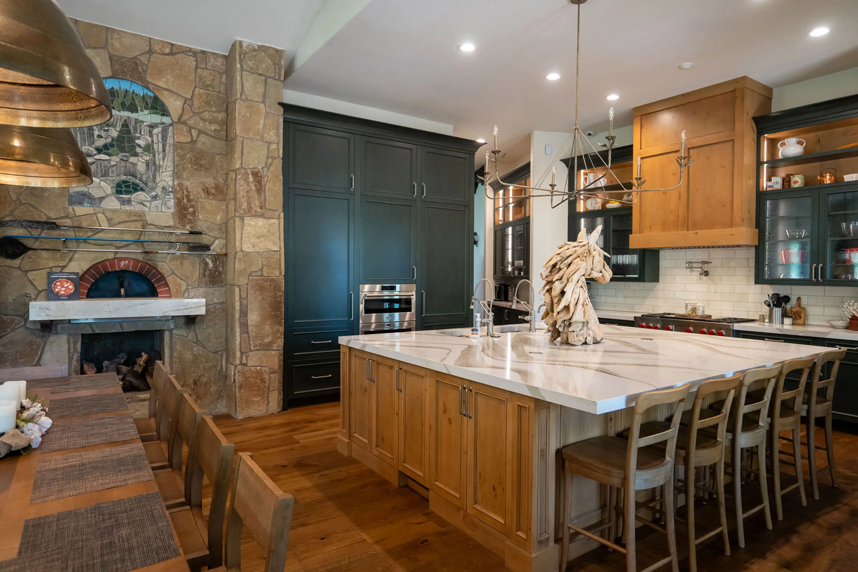 Finished kitchen with custom cabinetry, a stone island and pendant lighting